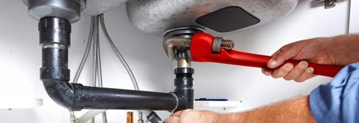 Garbage disposal repair technician tightening the sink drain and disposal connection in Huntsville, AL