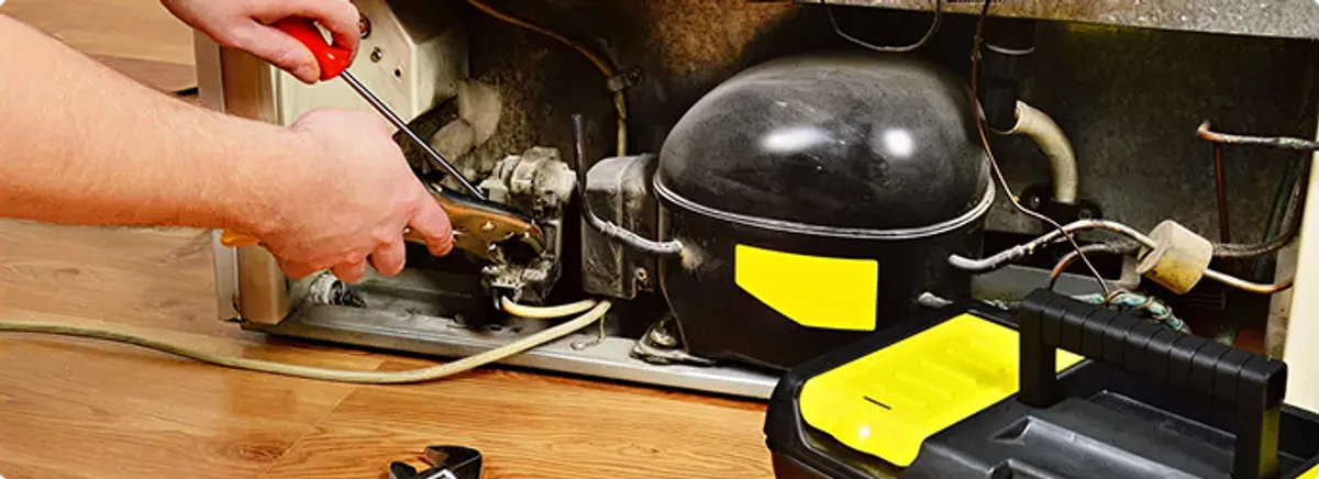 Refrigerator repair technician fixing the compressor and wiring in Huntsville, AL